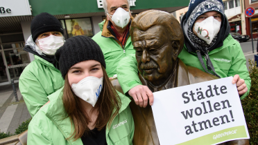 Greenpeace-Aktivisten mit Atemschutzmasken am Willy-Millowitsch-Denkmal in Köln