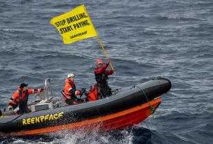 Greenpeace-Aktive mit Banner auf einem Boot