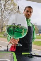 Greenpeace-Protest: Ein Mann hält ein riesiges Glas mit Pestizidcocktail in die Kamera