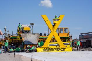 Auf Bannern fordern Aktive: „Beton stoppen – Natur schützen“. Vor der Baumaschine wurde ein fünf Meter großes gelbes X errichtet.