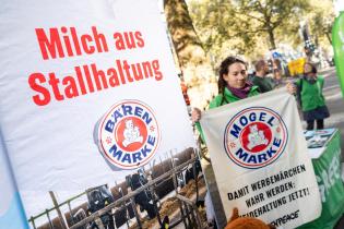 Ehrenamtliche am Infostand, großes Banner mit Bärenmarke-Logo und "Milch aus Stallhaltung". Eine Frau hält ein Banner "Damit Werbemärchen wahr werden: Weidehaltung jetzt!".