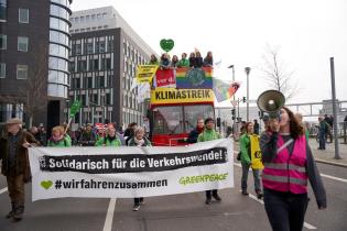 Banner "Solidarisch für die Verkehrswende" vor rotem Elektrobus in Berlin