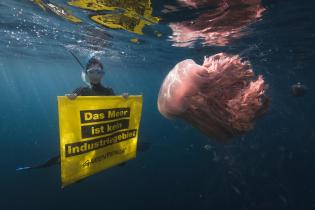 Greenpeace-Taucherhin hält 'Das Meer ist Kein Industriegebiet'  Banner neben Gelber Haarqualle vor Westaustralien