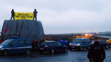 Greenpeace-Aktivisten stehen auf einem Reaktorbauteil auf einer französischen Straße