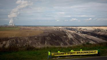 Ein Protestbanner "Zukunft statt Kohle" und im Hintergrund eine Braunkohlegrube und ein Kraftwerk