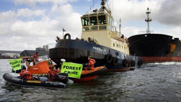 Greenpeace-Aktivisten vor einem Schiff im Amsterdamer Hafen, das Soja geladen hat. Sie halten Banner mit der Aufschrift "Forest Crime".