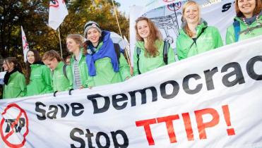 Acht Greenpeace-Aktivistinnen auf der Anti-TTIP-Demo in Berlin. Sie halten ein Banner mit der Aufschrift "Save Democracy - Stop TTIP"