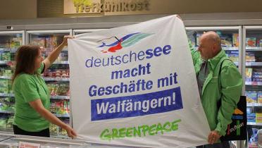 Zwei Greenpeace-Aktivisten halten ein Banner hoch: "deutsche See macht Geschäfte mit Walfängern".