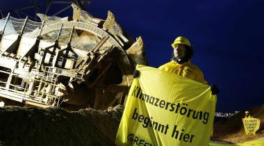 Greenpeace-Aktivist mit Banner vor riesigem Schaufelradbagger