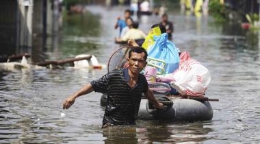 Mann im Hochwasser in Thailand rettet sein Hab und Gut auf einem Schlauchboot
