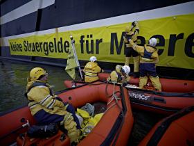 Mit Magneten befestigen Greenpeace-Aktivisten ihr Protestbanner an der Bordwand des Trawlers Jan Maria. Bremerhaven, Dezember 2011