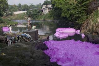 Auf dem Fluss Tullahan River (Philippinen) treibt lila Schaum. Flussaufwärts sind diverse Industrien angesiedelt. 2012