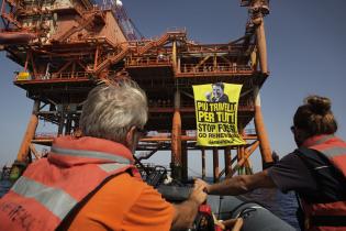 Greenpeace-Aktivisten fahren mit einem Schlauchboot auf eine Ölplattform zu, an der ein 120 m² großes Banner hängt