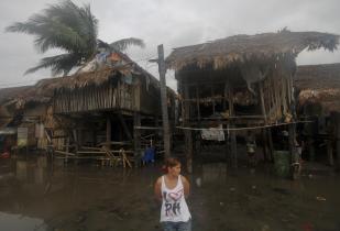 Eine Frau vor einem nahezu vollständig zerstörten Haus auf den Philippinen - Eine Folge des Taifuns.