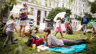 Verschiedene Menschen verweilen auf dem auf der Bergmannstraße in Berlin ausgelegten Rasen-