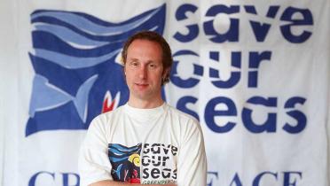 Peter Pueschel vor einem Banner "save our seas".