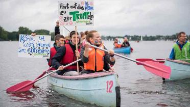 Jugendliche in einem Boot auf der Alster. Sie tragen ein Schild mit der Aufschrift "Hört auf, das Klima zu zerTRUMPeln"