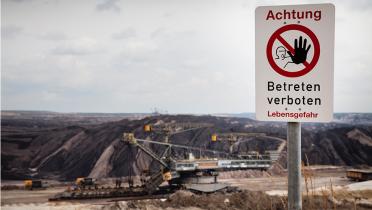 Braunkohle Tagebau von Vattenfall in der Lausitz. Ein Schaufelradbagger steht in einer Tagebaugrube. Warnschild von Vattenfall im Vordergrund.