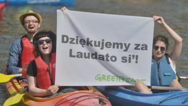 Polnische Aktivisten halten im Kajak ihr Banner in die Luft
