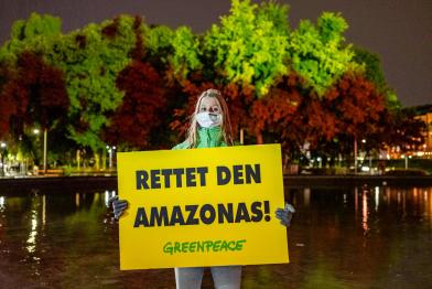 Greenpeace-Aktivistin mit Banner "Rettet den Amazonas"