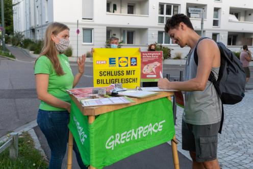 Ehrenamtliche der Greenpeace-Gruppe in Augsburg protestieren vor einem Edeka-Markt gegen Billig-Fleisch. Auf einem Banner ist zu lesen: "Schluss mit Billigfleisch!"