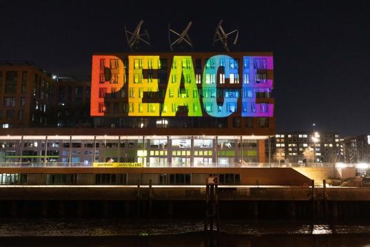 Mehrere Tage lang leuchtet in den frühen Morgen- und Abendstunden die Projektion der Buchstaben PEACE (FRIEDEN) in Regenbogenfarben als Zeichen der Solidarität und für den Frieden auf die Zentrale von Greenpeace Deutschland in Hamburg.