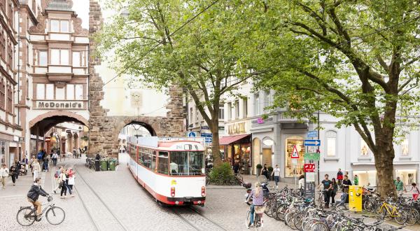 Verkehrs- und Wohninfrastruktur in Freiburg. Öffentliche Verkehrsmittel mit der Straßenbahn. Radfahrer:innen in der Stadt.