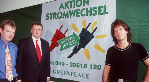 Drei Personen vor einem Plakat mit der Aufschrift "Aktion Stromwechsel"