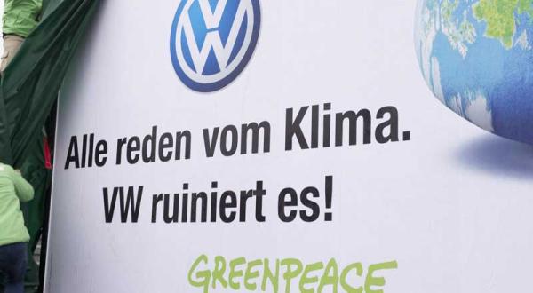 Aktivisten enthüllen Plakat vor einem VW Werksparkplatz im Dezember 2011