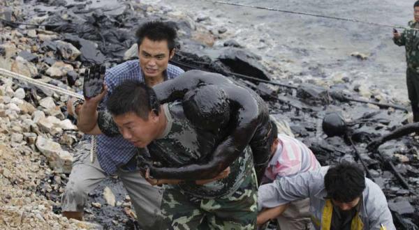 Helfer retten einen der beiden Feuerwehrmänner aus dem Öl im Juli 2010