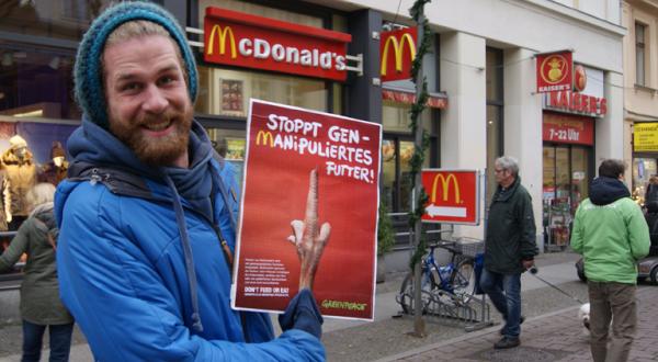 Ein Passant lässt ein Foto von sich mit einem Motiv gegen den Einsatz genamipulierten Futters bei McDonalds fotografieren