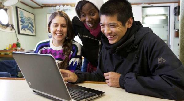 Drei Jugendliche sitzen vor einem Laptop und schauen sich etwas an.