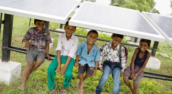 Kinder unter einer Solaranlage im indischen Ort Dharnai
