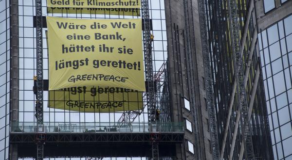 Greenpeace-Kletterer befestigen ein Banner an der Fassade der Deutschen Bank.