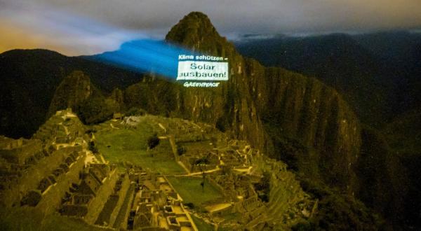 Eine Projektion "Klima schützen - Solar ausbauen!" wird von Greenpeace-Aktivisten auf den Berggipfel des Machu Piccu geworfen