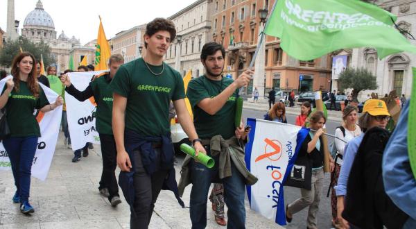 Gut ein Dutzend junger Leute läuft über eine Straße in Rom. Viele von ihnen tragen grüne T-Shirts mit dem Greenpeace-Schriftzug, einer hält eine Fahne mit dem Logo der Umweltschutzorganisation.