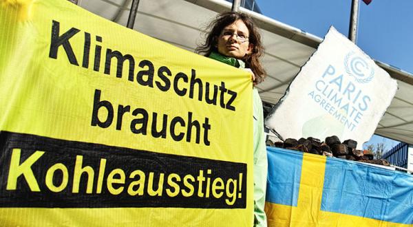 Aktivistin mit Banner "Klimaschutz braucht Kohleausstieg" vor der schweidischen Botschaft in Berlin
