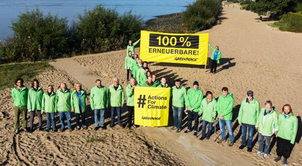 Zum Windrad formierte Greenpeace-Aktivisten stehen an der Elbe in Hamburg. 