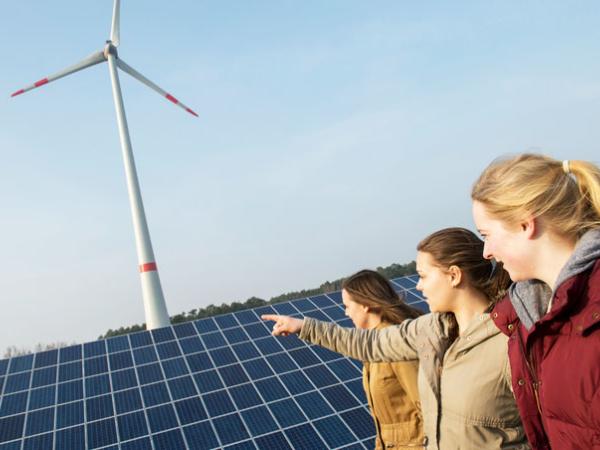 Jugendliche betrachten Solar- und Windkraftanlagen