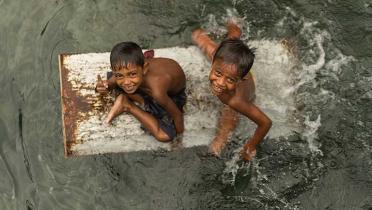 Bajau-Kinder paddeln auf einer alten herumschwimmenden Kühlschranktür 