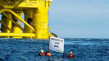 Zwei Schwimmer im Pazifik protestieren mit einem Banner vor der Polar Pioneer