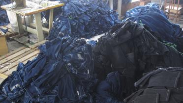 Berge von getragenen Jeans warten in einem Raum darauf, recycelt zu werden.