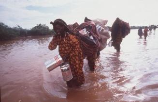 Überschwemmung in Somalia. Flüchtlinge tragen ihre Habseligkeiten durchs Wasser.  