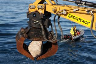 Aktivist:innen werfen von einem Schiff große Steine auf den Grund der Nordsee vor Sylt, um die Meeresfauna in dem Gebiet zu schützen. Das Meeresschutzgebiet ist durch Baumkurrenkutter und Kiesabbau bedroht. 