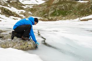 Ein Aktivist nimmt Proben am mit Schnee und Eis bedeckten Macun See in der Schweiz