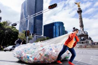 Kunststoffverbrauch in Mexiko: Eine Person trägt eine große Tasche mit Plastikflaschen. 