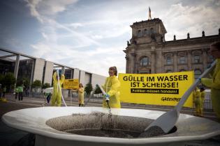 Aktive lassen über einen Schlauch Gülle in einen drei Meter großen Teller vor dem Reichstag in Berlin laufen.