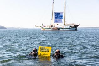 Im Hintergrund das Schiff Beluga, davor zwei Schwimmende mit einem Banner: Gülle ist Gift für die Ostsee
