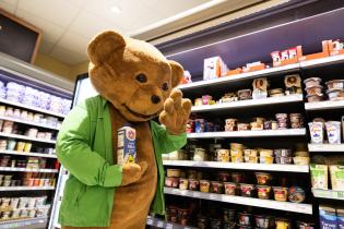 Aktivist in einem Bärenkostüm hält im Supermarkt eine Bärenmarkemilch.