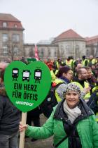 Aktivistin mit grünem Schild "Ein Herz für Öffis"